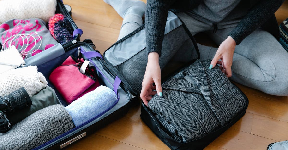 Woman organizing clothing and camera gear using a packing list for travel in an open suitcase