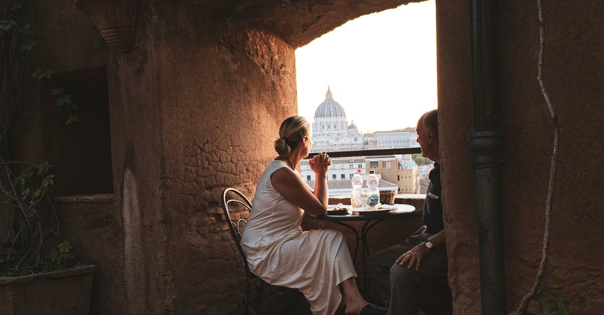 Pareja disfrutando de una cena romántica con vistas a la cúpula de San Pedro en Roma durante el atardecer.