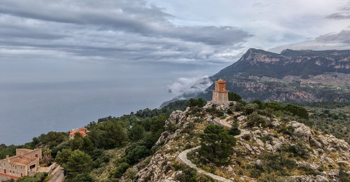 Rotsachtige kustlijn van Mallorca met weelderig groen onder een bewolkte lucht bij slecht weer.