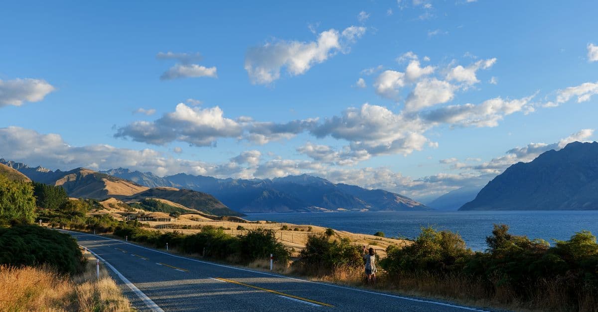 Scenic New Zealand mountain highway with lake views, capturing the cost of a two-week US road trip.