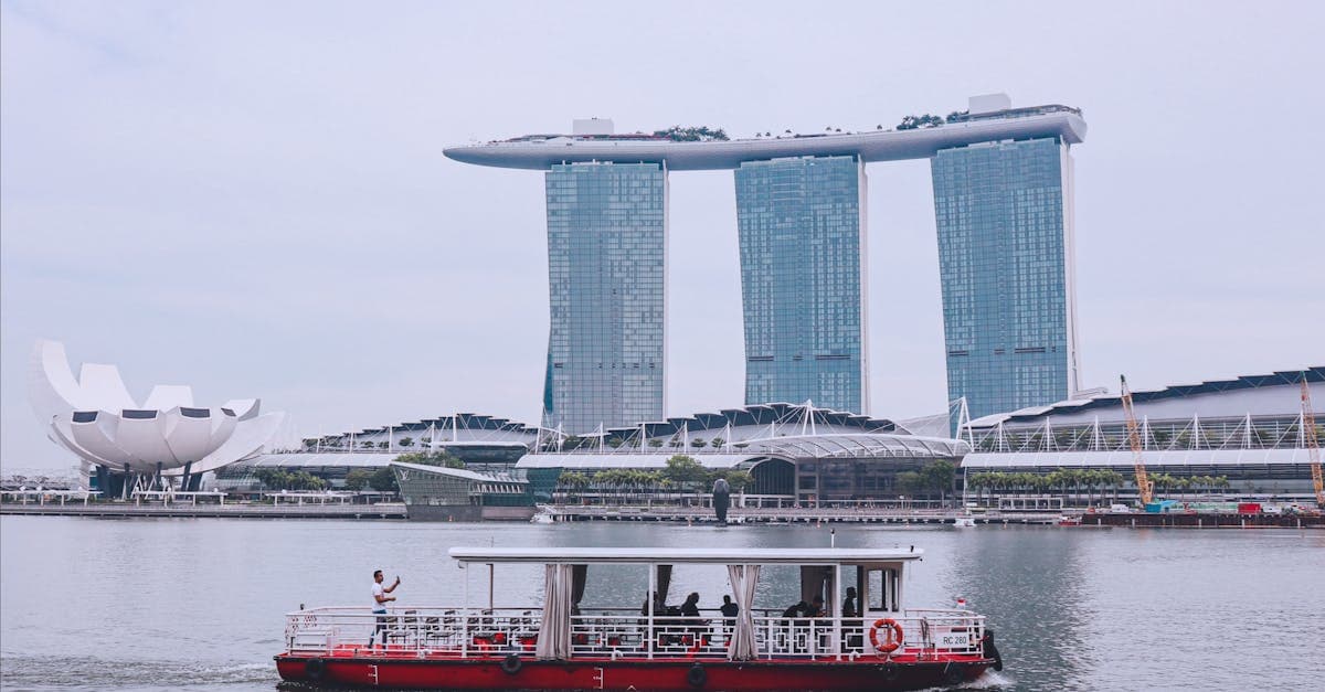 Traditional Singapore riverboat passing Marina Bay Sands, why buying travel insurance before arrival is always smarter.