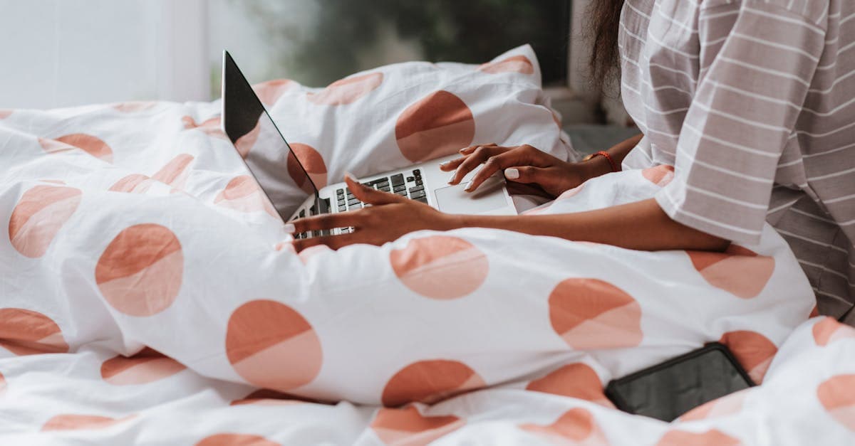 Femme sur son lit avec un ordinateur portable testant l'autonomie et les débits d'un boitier wifi