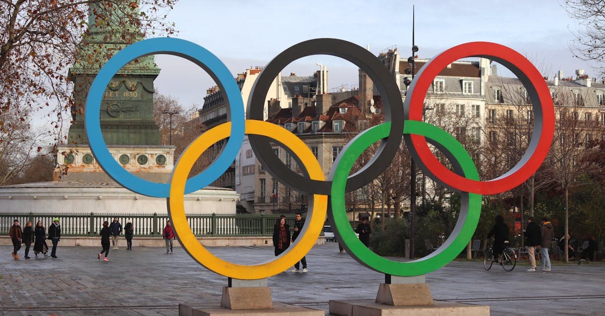 Anneaux olympiques iconiques devant un panorama urbain, symbole du programme JO 2026 en Italie