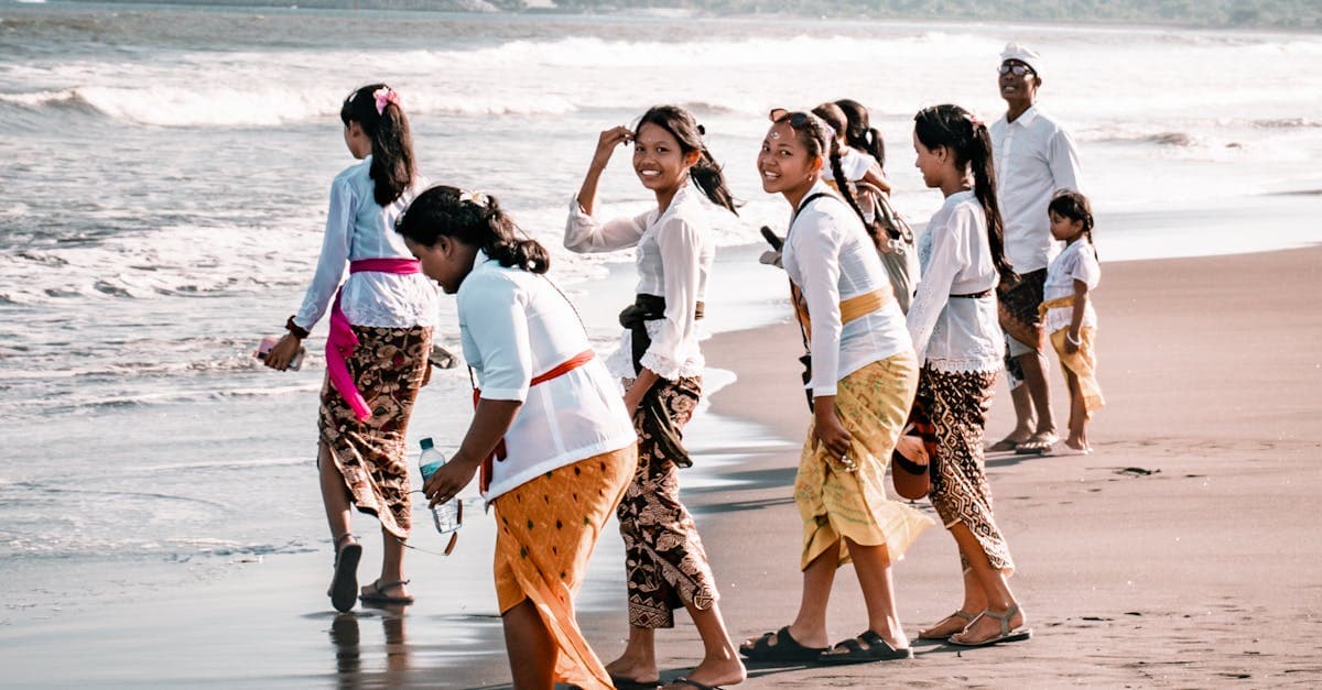 Groupe en tenues traditionnelles sur une plage ensoleillée de Bali, meilleure période en famille pendant la saison des pluies