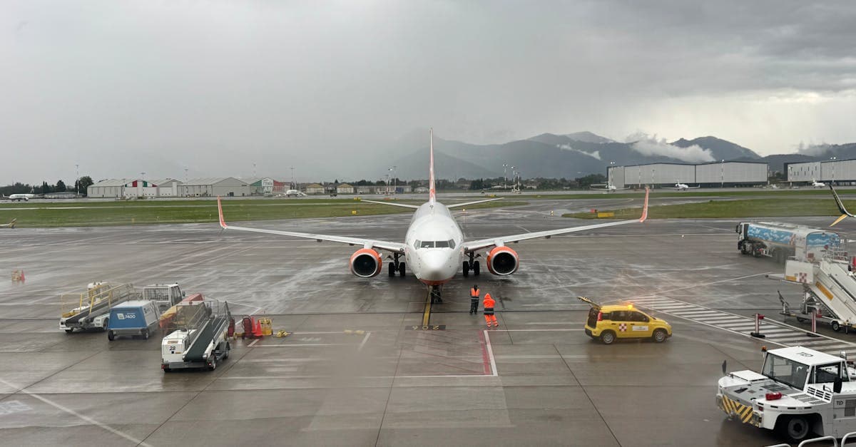 Aereo commerciale sul piazzale bagnato dell'aeroporto Leonardo da Vinci con montagne sullo sfondo