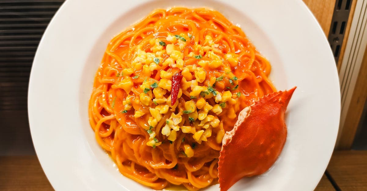 Plate of vibrant seafood pasta topped with sweetcorn and crab in a cozy setting.