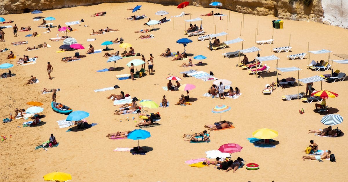 Praia movimentada em Faro, Portugal, repleta de banhistas e guarda-sóis nos meses de verão na europa