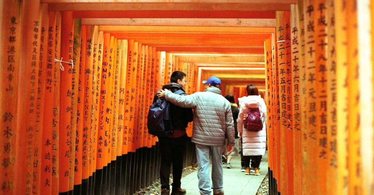 Tourists walking through the iconic vermilion torii gate tunnel at Kyoto's Fushimi Inari Shrine, a japan itinerary highlight