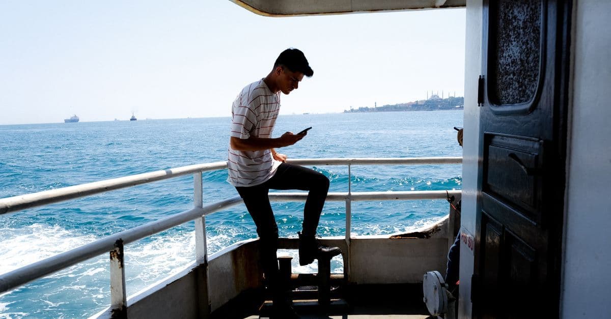 Traveller checking phone connectivity options aboard a cruise ship on a sunny day at sea.
