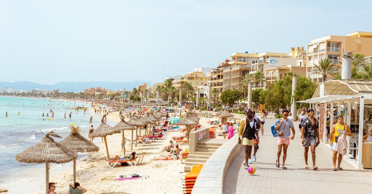 Sunbathers and swimmers enjoying a bustling Ibiza beach on a warm Mediterranean summer's day.