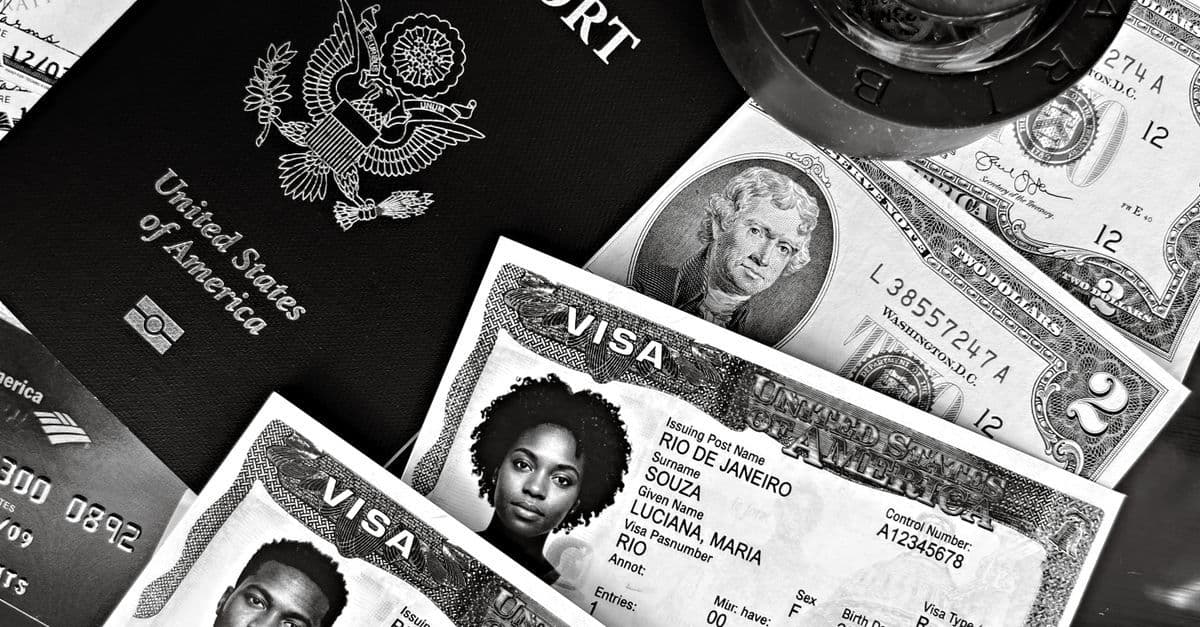 A U.S. passport, visa documents, and banknotes are arranged together, suggesting travel paperwork and expenses.