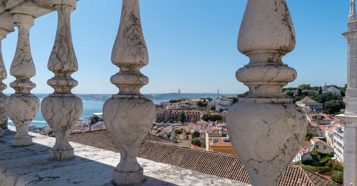 Centro histórico de Lisboa e rio Tejo vistos de balaustrada clássica de pedra, símbolo do verão na europa