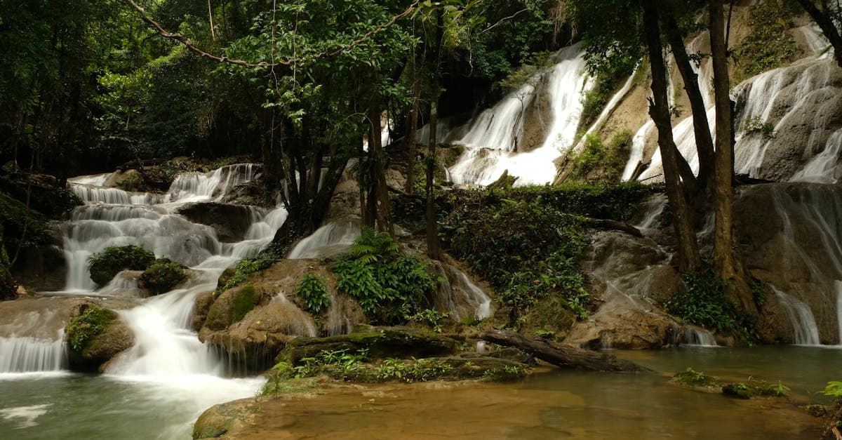 Lush waterfall cascading through Kanchanaburi jungle, best time to visit Thailand for budget savings in wet season