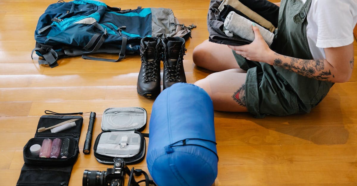 Woman organising clothes and camping gear on floor, essential items in travel checklist.