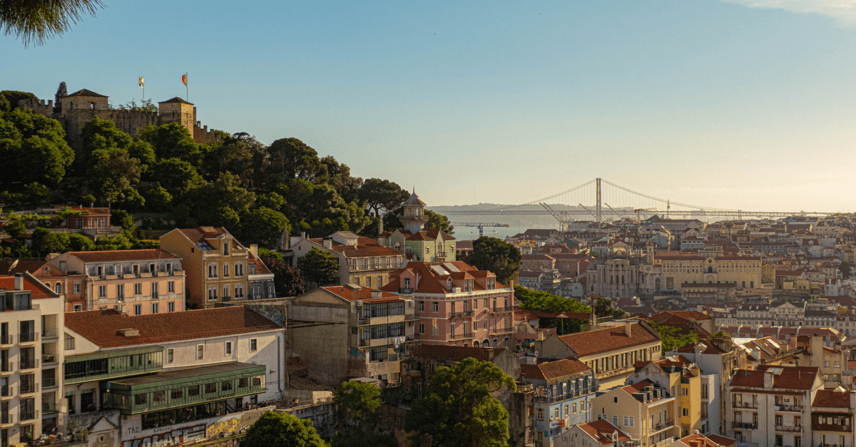 Arquitetura colorida de Lisboa com vista para a icônica Ponte 25 de Abril em dia ensolarado