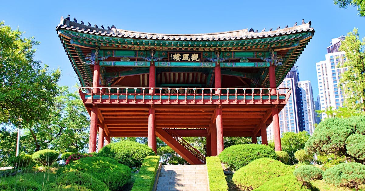 ソウル 観光の定番スポット、晴れた青空のもと現代都市を背景に佇む美しい韓国の伝統的な亭閣