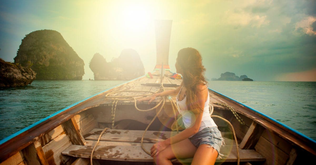 Kobieta na tradycyjnej tajskiej łodzi o zachodzie słońca w Krabi podczas chłodnego sezonu suchego.