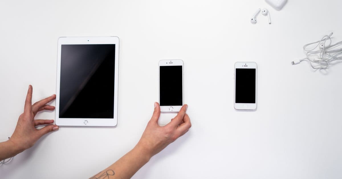 Vista dall'alto di iPhone, iPad e auricolari su superficie bianca, guida al ripristino eSIM dopo riparazione iPhone