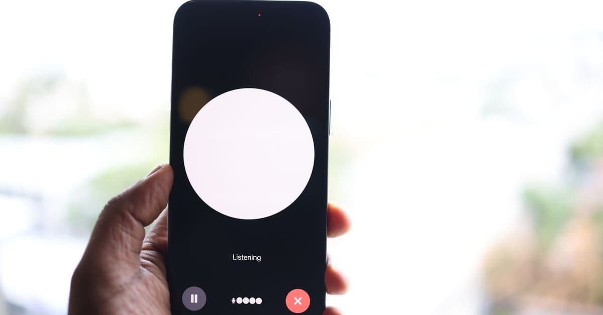 Close-up of a hand holding a smartphone with a voice assistant interface ready to respond.