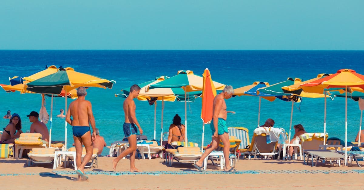 Farverige strandsombreller og badegæster på en solrig strand på Kreta i den varme oktober