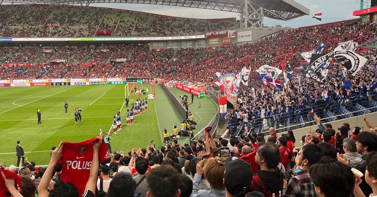 日本のスタジアムで旗を振りながら声援を送るファンたちによる白熱したサッカーの試合。