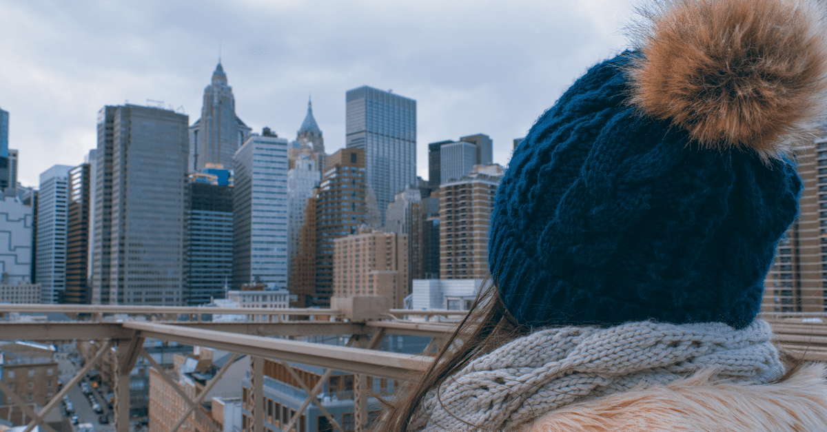 Mulher com gorro de inverno observa o skyline enquanto experimenta o clima em Nova York