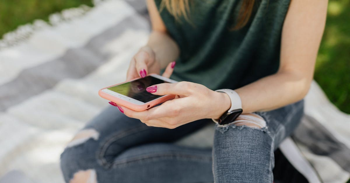 Kobieta sprawdza limit t mobile roaming na smartfonie siedząc na kocu w słonecznym parku