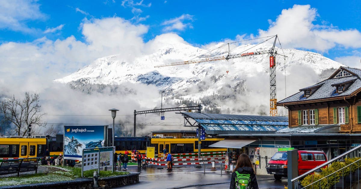 Reisende mit Koffer auf dem Weg zum Bahnhof, umgeben von schneebedeckten Bergen beim Jungfraujoch.