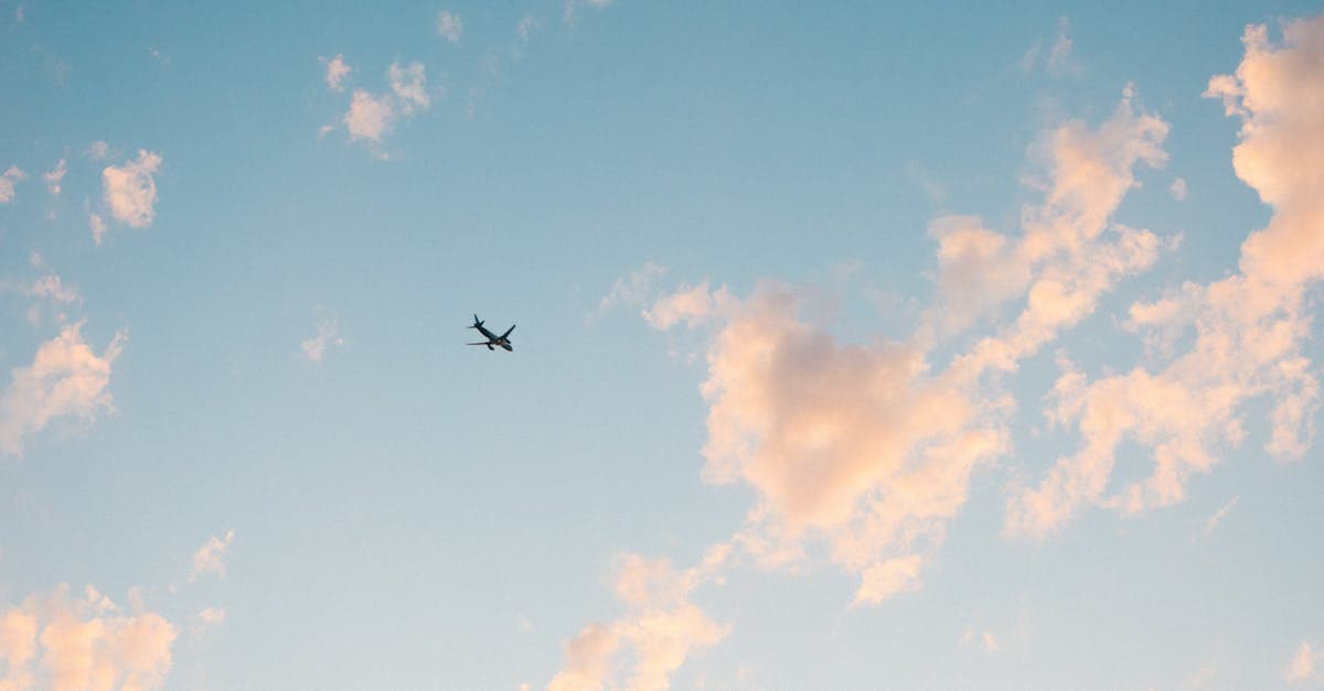 Einzelnes Flugzeug am bewölkten blauen Himmel, Symbol für flexible Reisedaten im Preiskalender