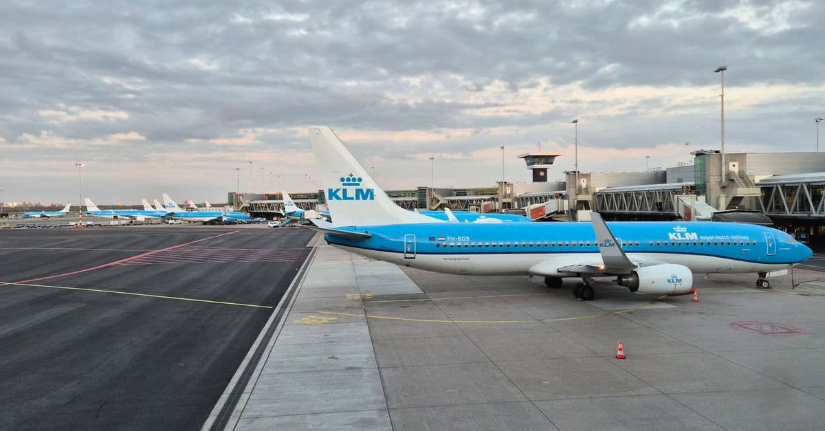 KLM-vliegtuig op de startbaan van Amsterdam Airport Schiphol, klaar voor vertrek op een heldere dag.