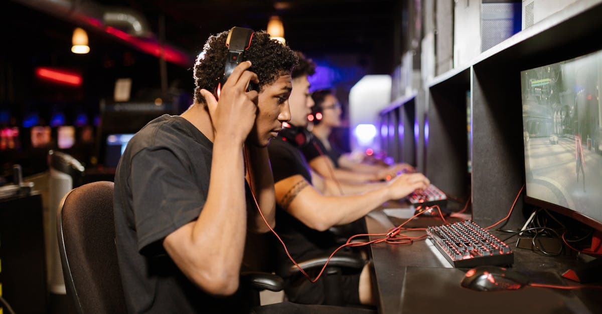 Young adults focused on video games in a modern internet cafe gaming lounge.