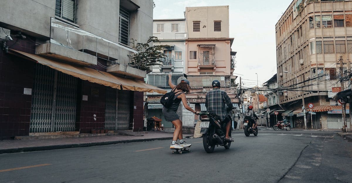 A skateboarder holds onto a motorcycle on a city street in Ho Chi Minh City, capturing urban life.