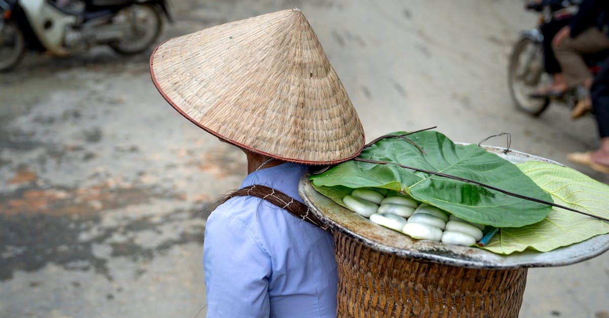 Vietnamesisk gadesælger bærer snacks i en flettet kurv med bananblade og keglehat