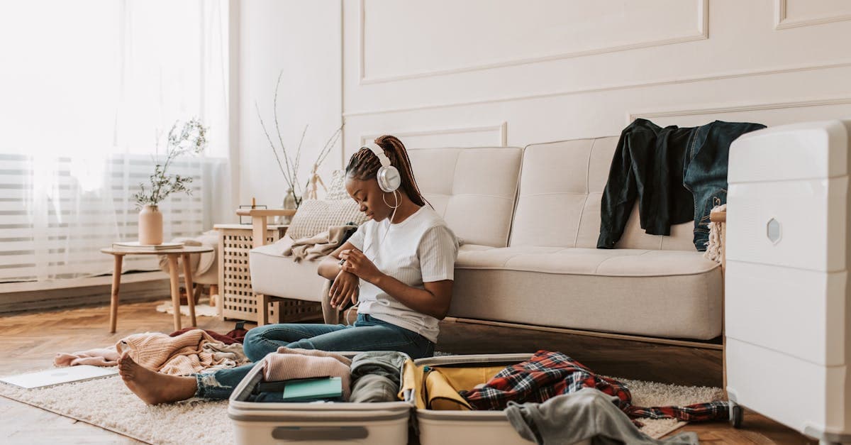 Young woman surrounded by clothing items applying the 5-4-3-2-1 packing rule to her open suitcase