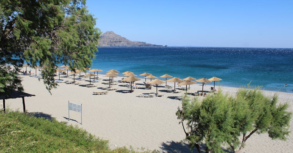 Rolig sandstrand med solparasol på Kreta og klart blåt hav på en perfekt sommerdag