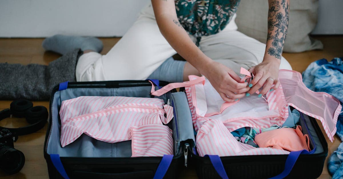Woman kneeling on her bedroom floor with an open suitcase, working through a packing list for holiday