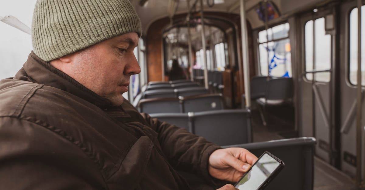 Mand i grøn hue bruger sin smartphone i en sporvogn i Sarajevo med lokalt simkort