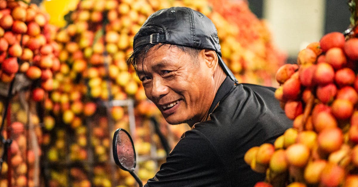 Joyful Vietnamese fruit vendor surrounded by fresh lychees at a Bac Giang province market